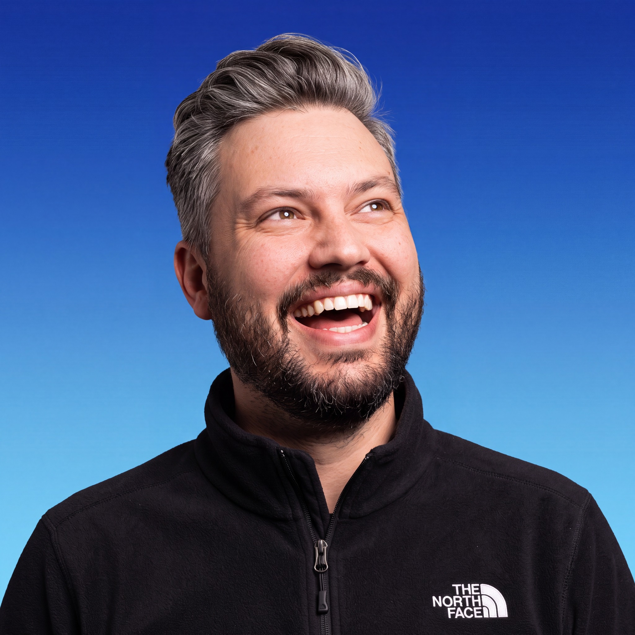 Garth Manthé laughing against a vivid blue background